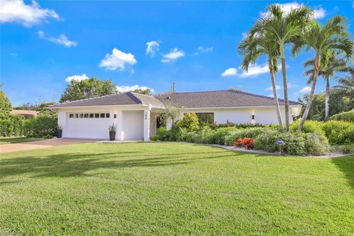 Ranch-style house featuring a front lawn, stucco siding, driveway, and a garage