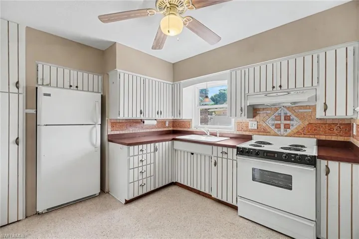 Kitchen featuring white cabinetry with vertical detailing, a white electric range, and a white top-freezer refrigerator