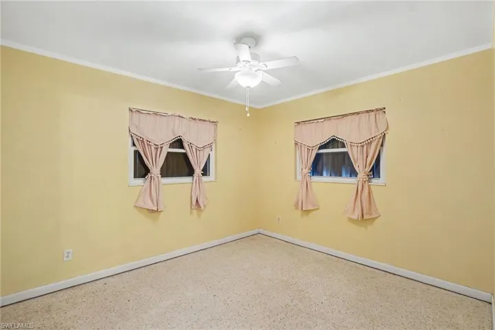 Interior room featuring two windows, white trim, and a ceiling fan