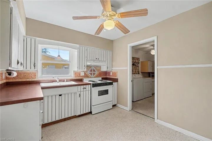 Kitchen featuring white wood-finish cabinetry, a drop-in sink, and a white electric range