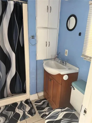 Bathroom with tile patterned floors, vanity, and curtained shower