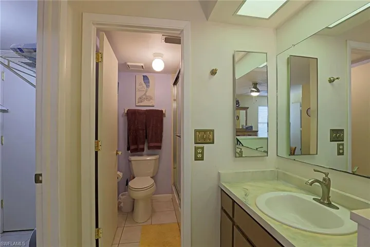 Bathroom featuring a single vanity with an integrated sink, brushed nickel faucet, and a wall-mounted mirror