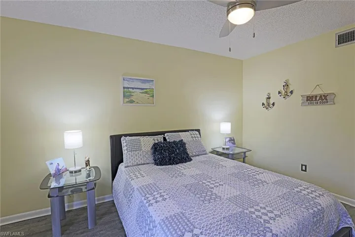Bedroom featuring light-toned walls, wood-finish flooring, and a ceiling fan with integrated lighting