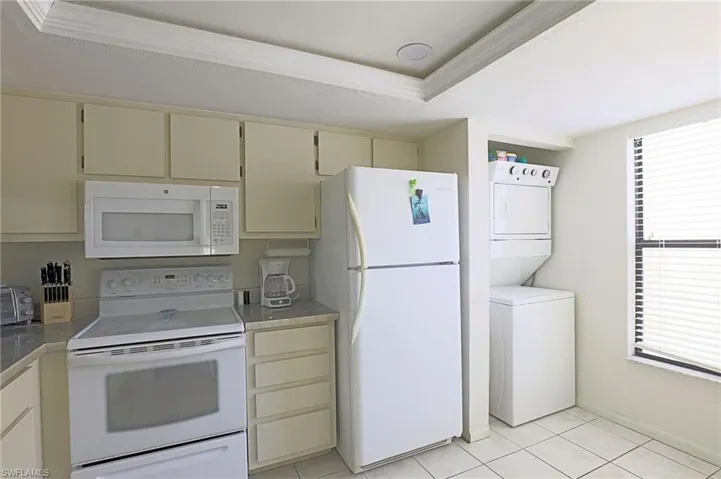 Kitchen area featuring white appliances, light-toned cabinetry, light countertops, and tile flooring