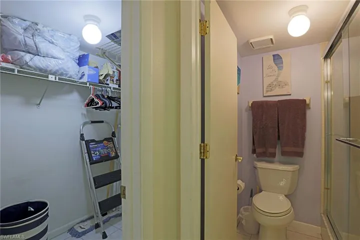 Compact bathroom featuring a toilet, wall-mounted towel rack, and glass-enclosed shower