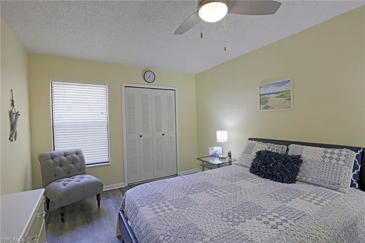 Bedroom featuring wood-finish flooring, a window with blinds, a bi-fold closet, a ceiling fan with integrated lighting, and neutral wall tones