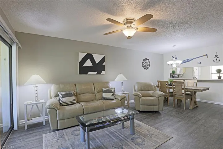 Spacious living area featuring wood-finish flooring, a ceiling fan with integrated lighting, and a sliding glass door