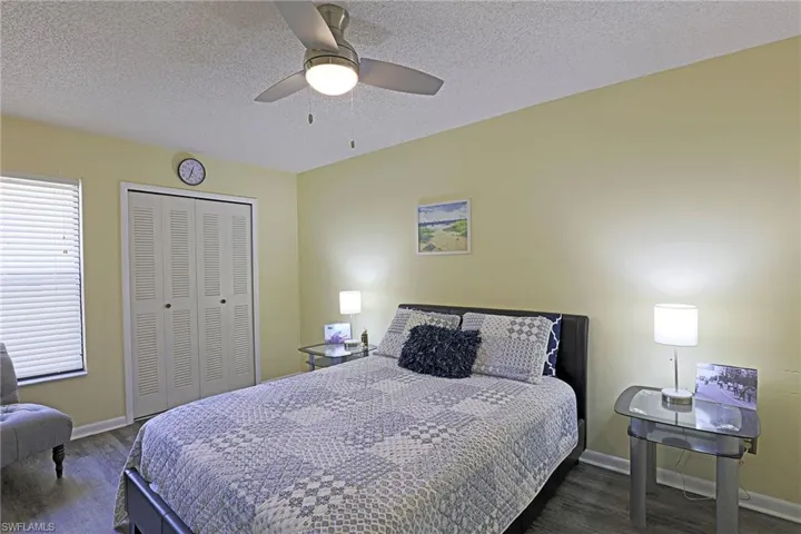 Bedroom featuring wood-finish flooring, a ceiling fan with integrated lighting, and a window with horizontal blinds