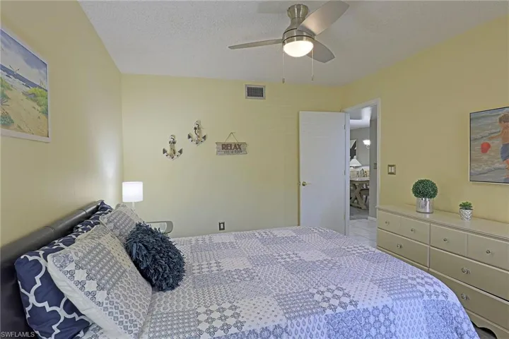 Bedroom featuring a ceiling fan with integrated lighting, textured ceilings, and a light-colored wall finish
