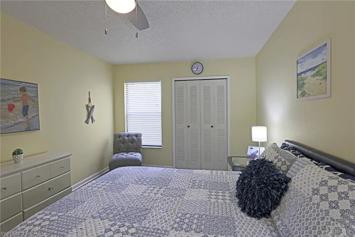 Bedroom featuring light yellow walls, a ceiling fan with integrated lighting, a window with horizontal blinds, and a built-in closet with bi-fold doors