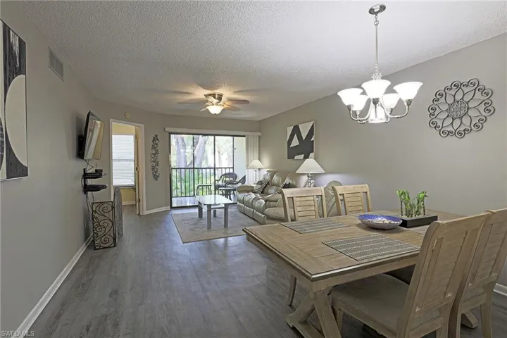 Open-concept living and dining area featuring wood-finish flooring, neutral wall tones, and a ceiling fan