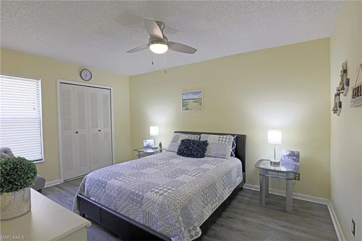 Spacious room featuring wood-finish flooring, a ceiling fan with integrated lighting, louvered bi-fold closet doors, and horizontal window blinds