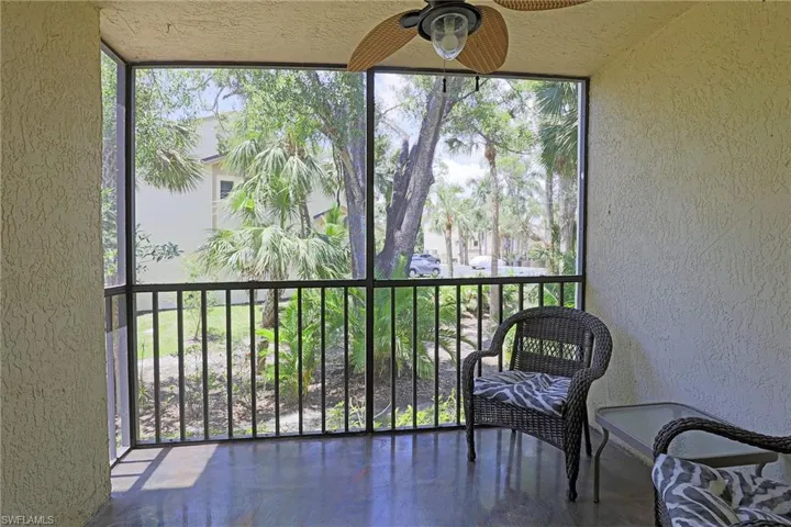 Screened patio featuring a ceiling fan with light fixture, textured walls, and a dark tile floor