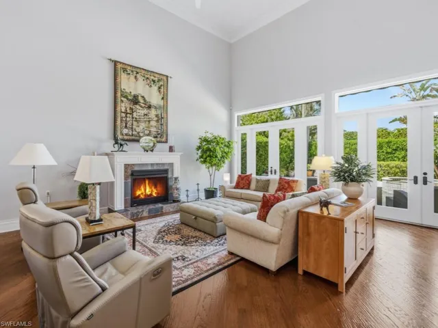 Living area with french doors, a high ceiling, dark wood finished floors, ornamental molding, and a tiled fireplace