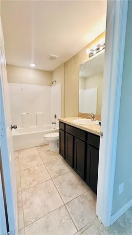 Bathroom featuring vanity, bathtub / shower combination, a textured ceiling, and light tile patterned flooring