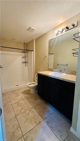 Bathroom featuring vanity, a shower stall, a textured ceiling, and light tile patterned floors