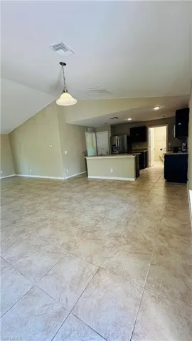 Unfurnished living room with vaulted ceiling and recessed lighting