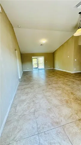 Spare room featuring light tile patterned floors and vaulted ceiling