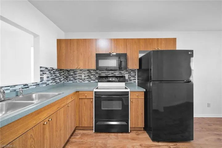 Kitchen featuring black appliances, wood finish cabinets, and light wood-style floors