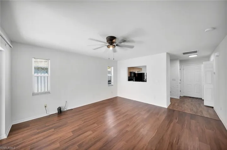 Unfurnished living room with a ceiling fan and dark wood-style flooring