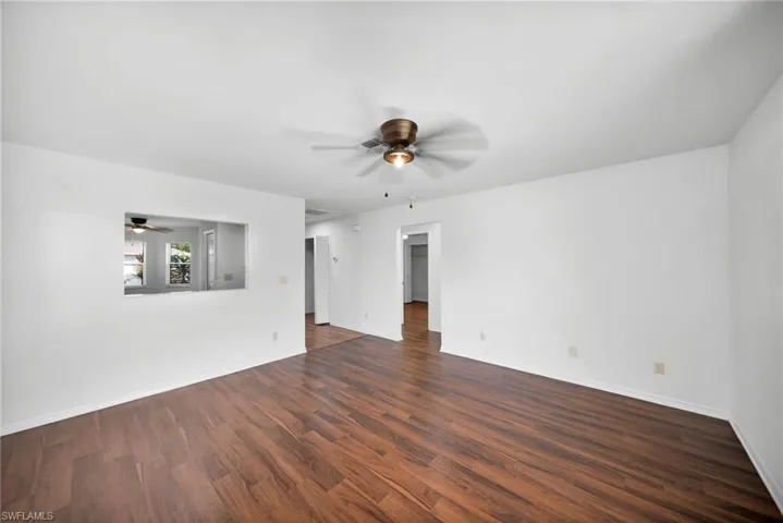 Empty room with a ceiling fan and dark wood-style flooring