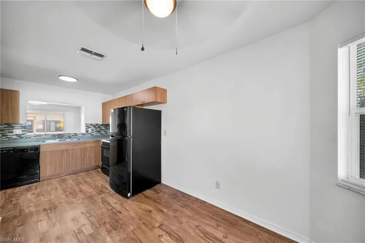 Kitchen with black appliances, light wood-style floors, tasteful backsplash, light countertops, and modern cabinets