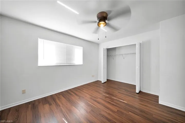 Unfurnished bedroom featuring a ceiling fan, dark wood-style flooring, and a closet