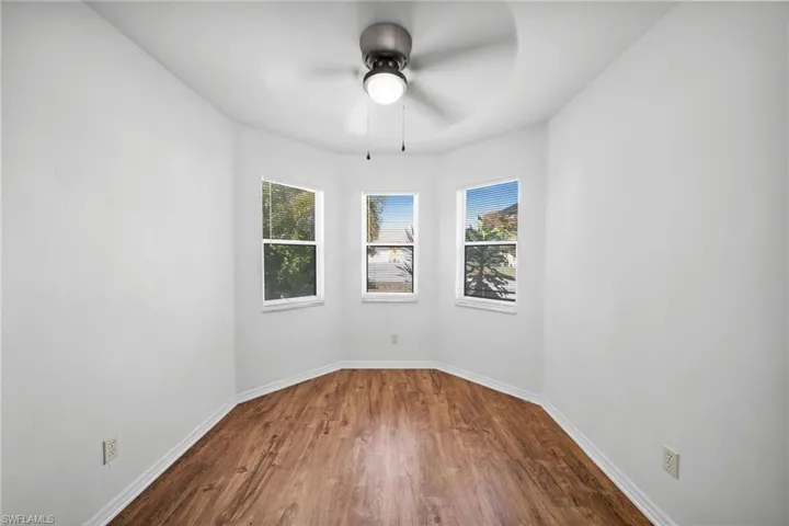 Unfurnished room with dark wood-type flooring and a ceiling fan