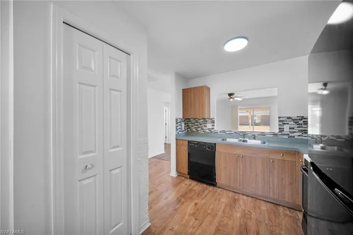 Kitchen featuring wood finish cabinetry, dishwasher, light wood-style floors, and tasteful backsplash