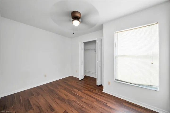 Unfurnished bedroom with dark wood-style flooring, ceiling fan, and a closet