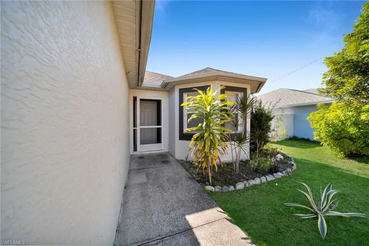 Property entrance featuring stucco siding and a yard