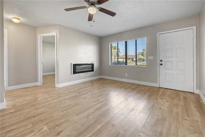 Unfurnished living room featuring light wood-type flooring, heating unit, a textured ceiling, and ceiling fan