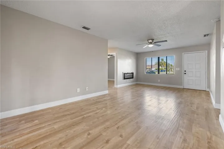 Unfurnished living room featuring a textured ceiling, light hardwood / wood-style floors, and ceiling fan