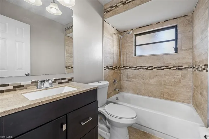Full bathroom featuring vanity, tiled shower / bath, and toilet