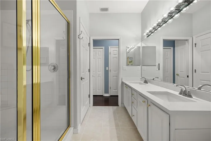 Bathroom with vanity, a shower with shower door, and tile patterned flooring
