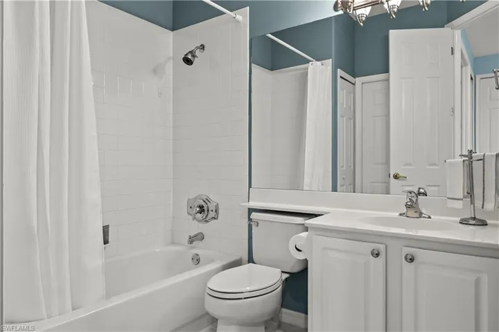 Full bathroom with vanity, shower / bath combo with shower curtain, and toilet