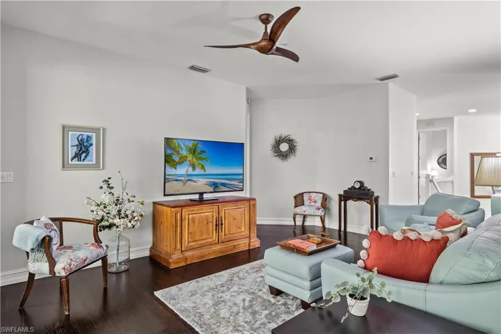 Living room with ceiling fan and dark hardwood / wood-style flooring
