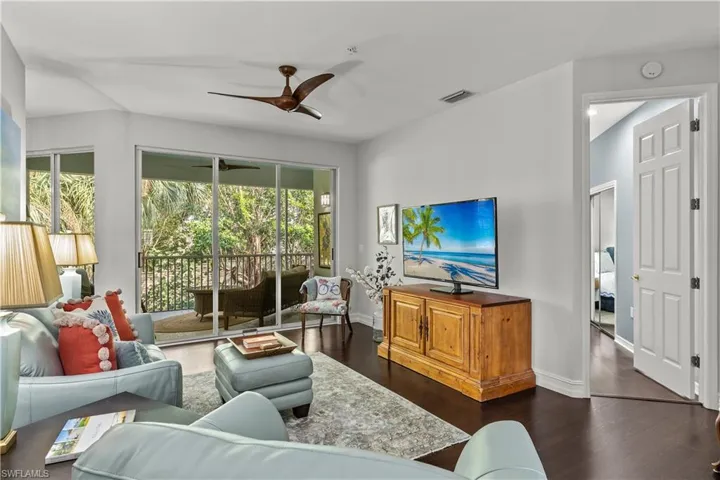 Living room with ceiling fan and dark hardwood / wood-style flooring