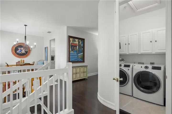 Laundry room featuring washer and dryer, hardwood / wood-style flooring, cabinets, and a chandelier
