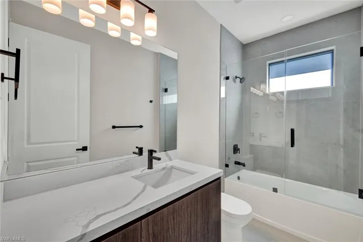 Full bathroom with bath / shower combo with glass door and vanity