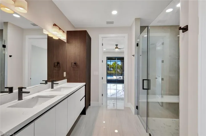 Bathroom featuring double vanity, a stall shower, recessed lighting, and ceiling fan