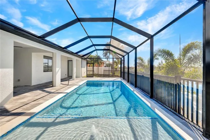 View of pool featuring a sunroom, glass enclosure, and a patio