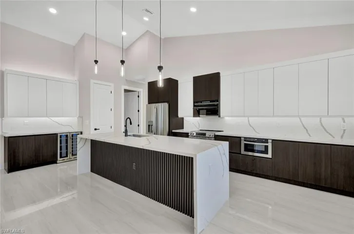 Kitchen with white cabinetry, dark brown cabinetry, a center island with sink, modern cabinets, and high vaulted ceiling