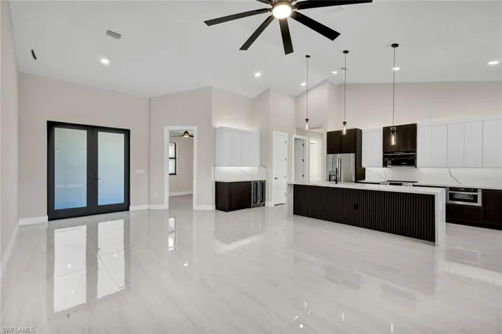 Kitchen featuring a spacious island, ceiling fan, high vaulted ceiling, pendant lighting, and modern cabinets