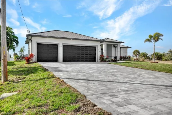 View of front of property featuring a front lawn, decorative driveway, a garage, and stucco siding