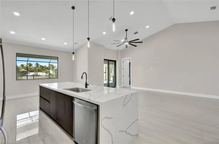 Kitchen featuring modern cabinets, dark brown cabinets, stainless steel appliances, light stone counters, and decorative light fixtures