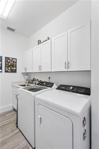 Generous laundry room has storage cabinets and sink.