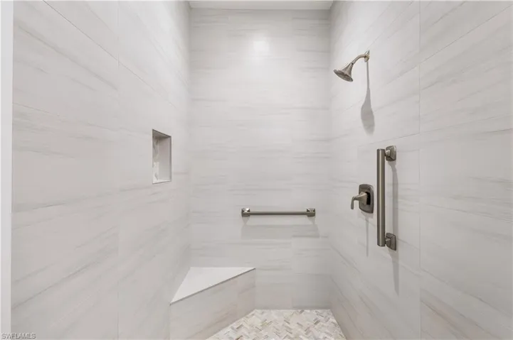Oversized walk in shower with niche and bench seating.  Floor to ceiling tile. Grab bar for safety.