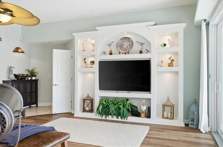 Living room featuring built in features, light wood-type flooring, and a ceiling fan