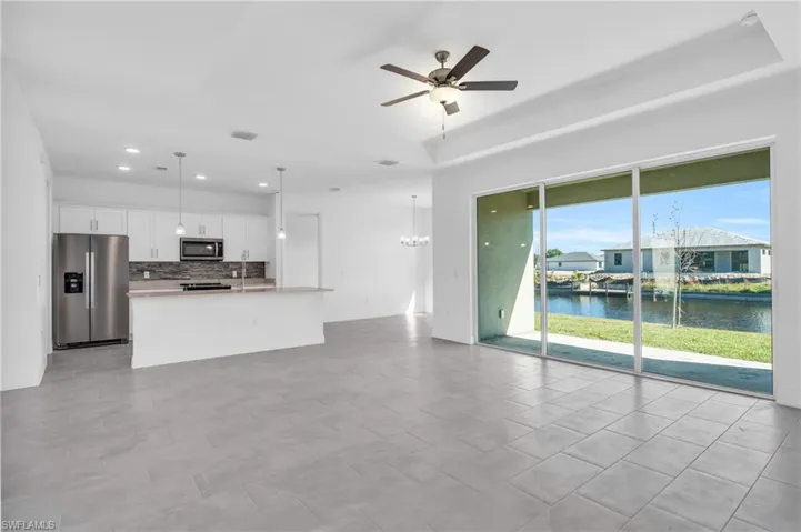 Unfurnished living room with ceiling fan, a water view, and a tray ceiling